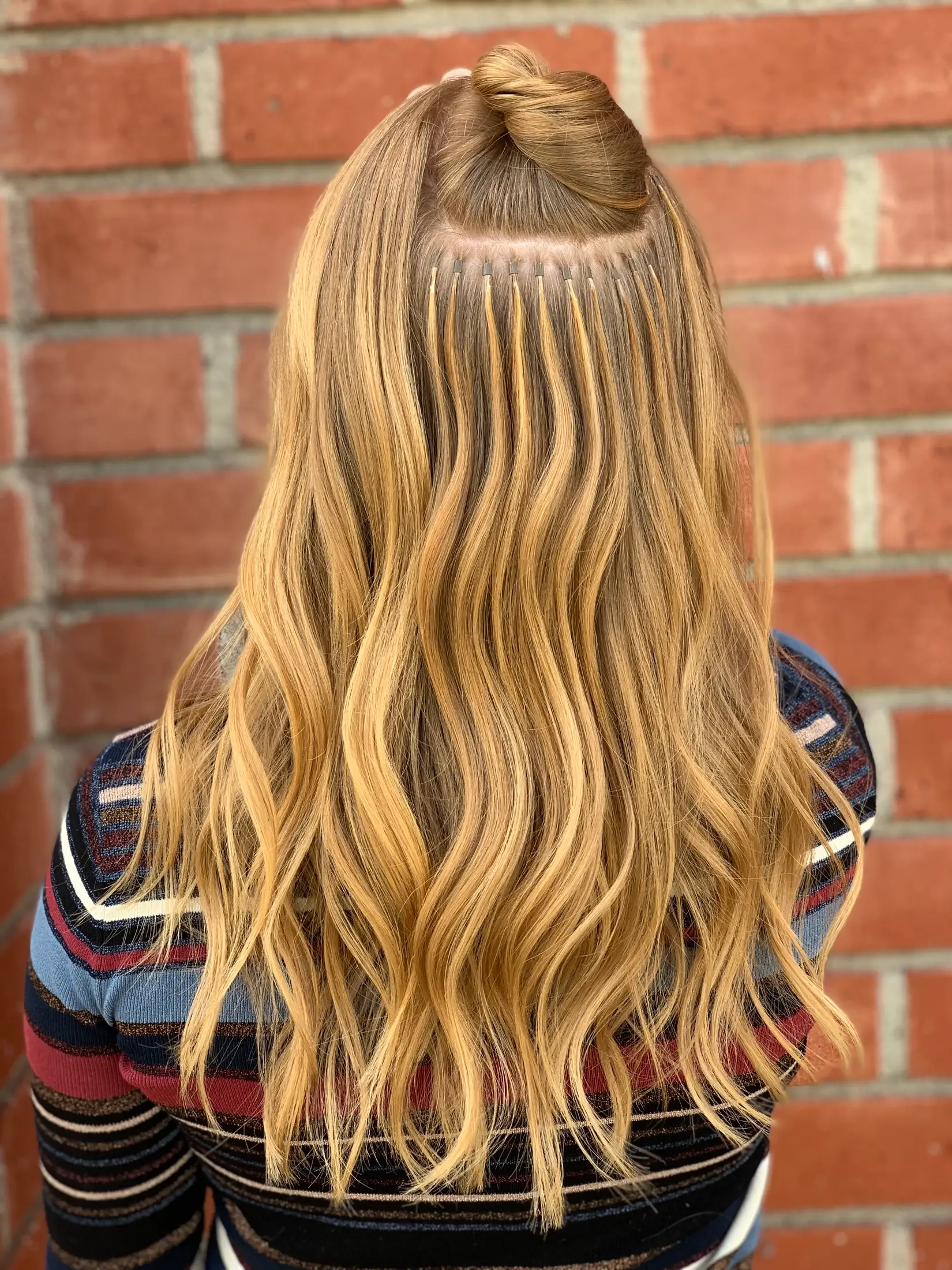 Extension rows visible at the part before the hair is brushed down over them